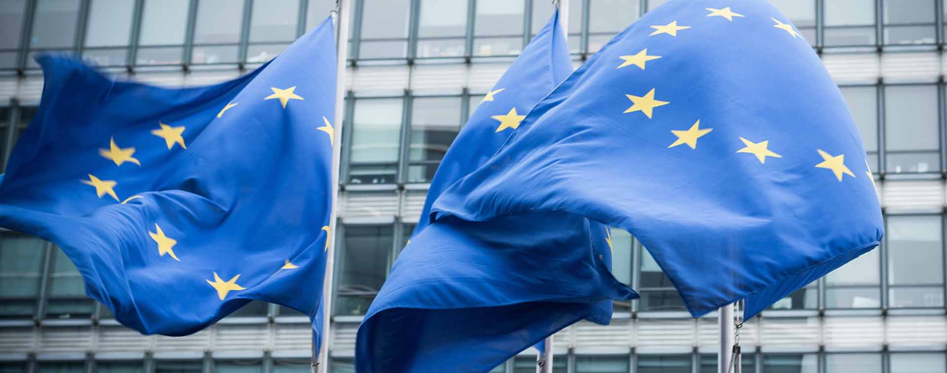 Three waving UN flags in front of an office building.