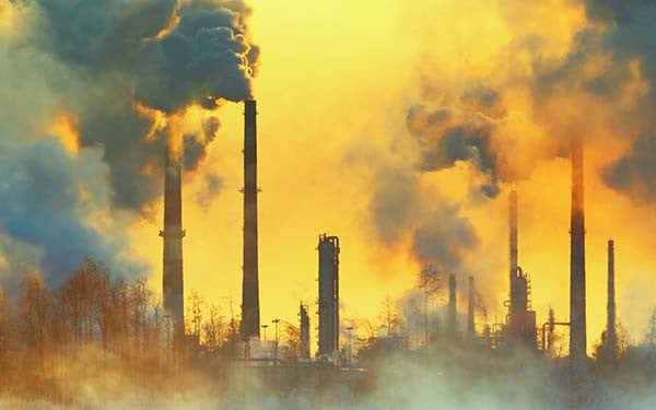 Orange sky being filled by smoke from various smokestacks. 